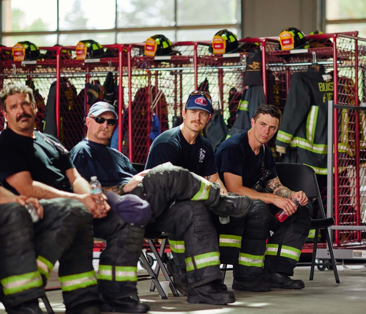 Firefighters in training with uniforms and helmets in the background
