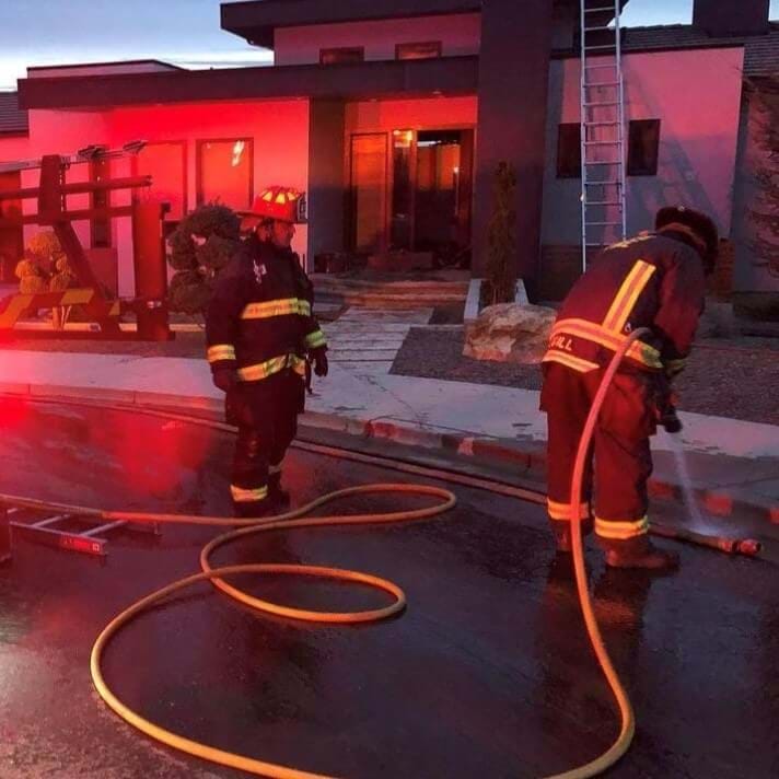 Two firefighters at night wearing full gear.