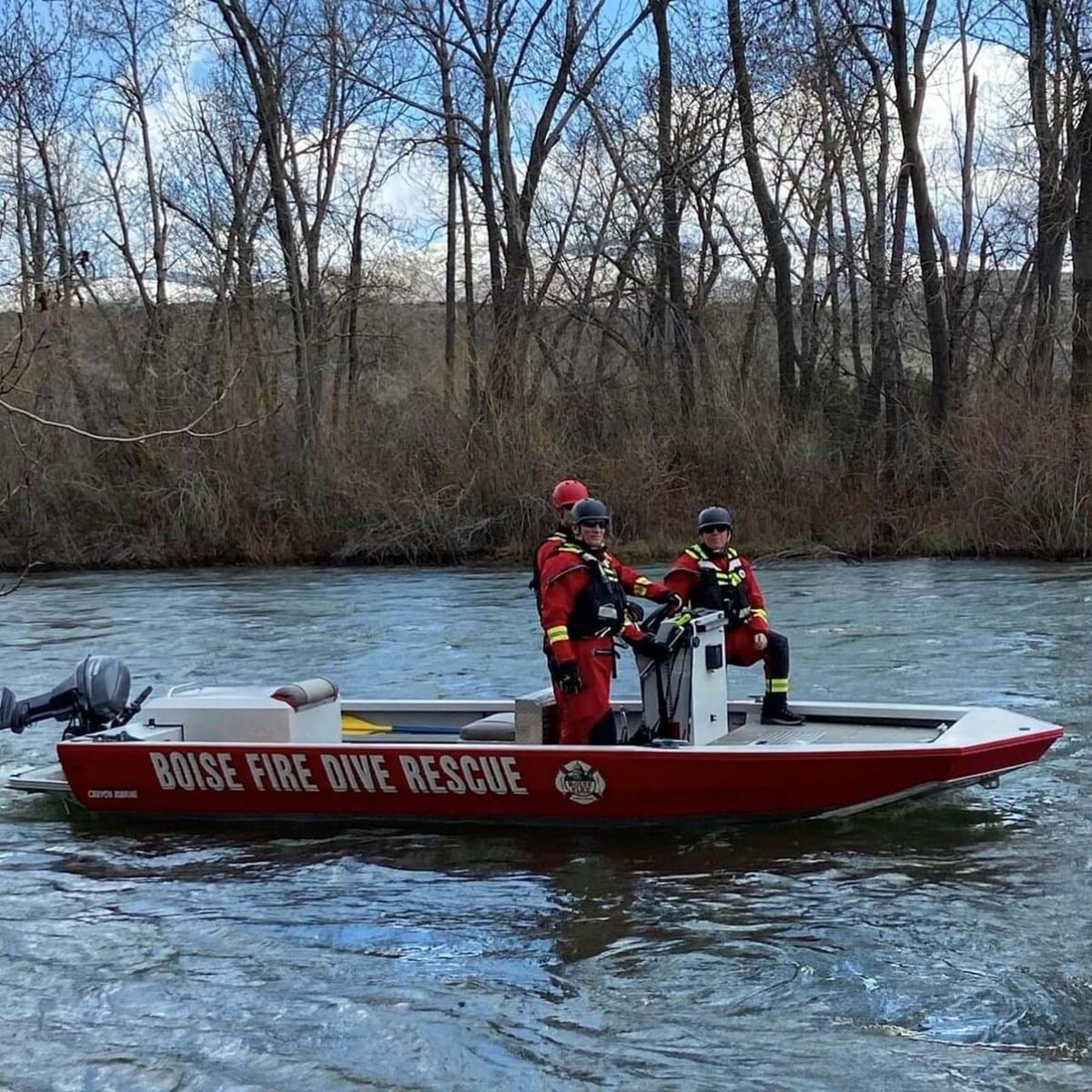Firefighters at standing on a boat on the Boise River.