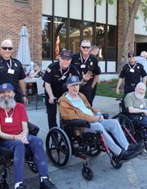 Group of firefighters standing next to several people who use wheelchairs.