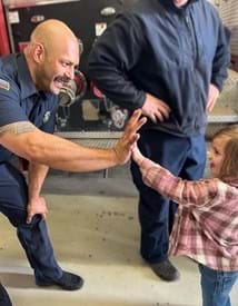 Firefighter giving a small child a high five.