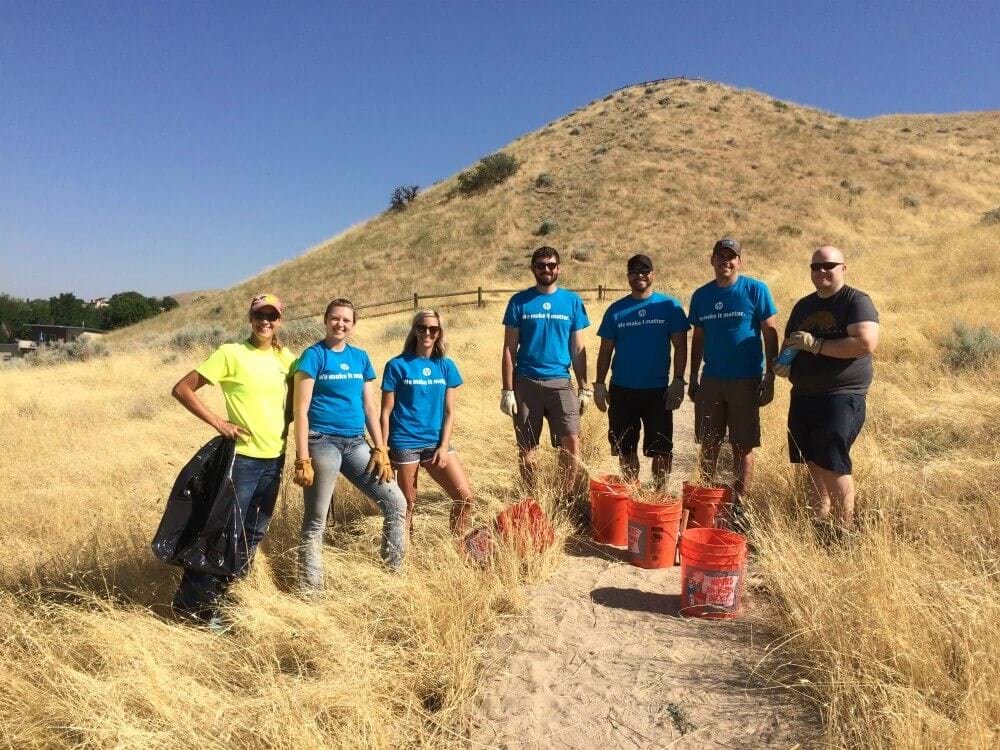 Group of people standing on a trail holding trash bags