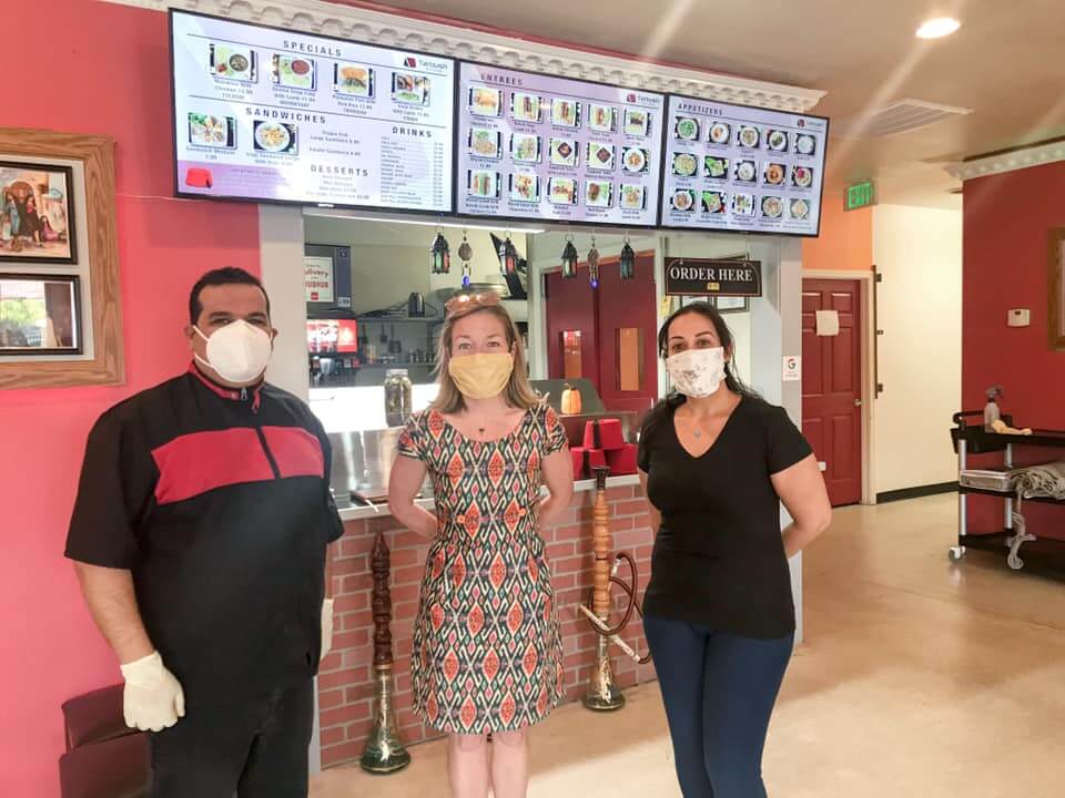 Mayor stands with two employees at restaurant. All are wearing face masks.