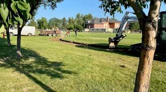 Construction equipment begins to dig the trail in grassy area