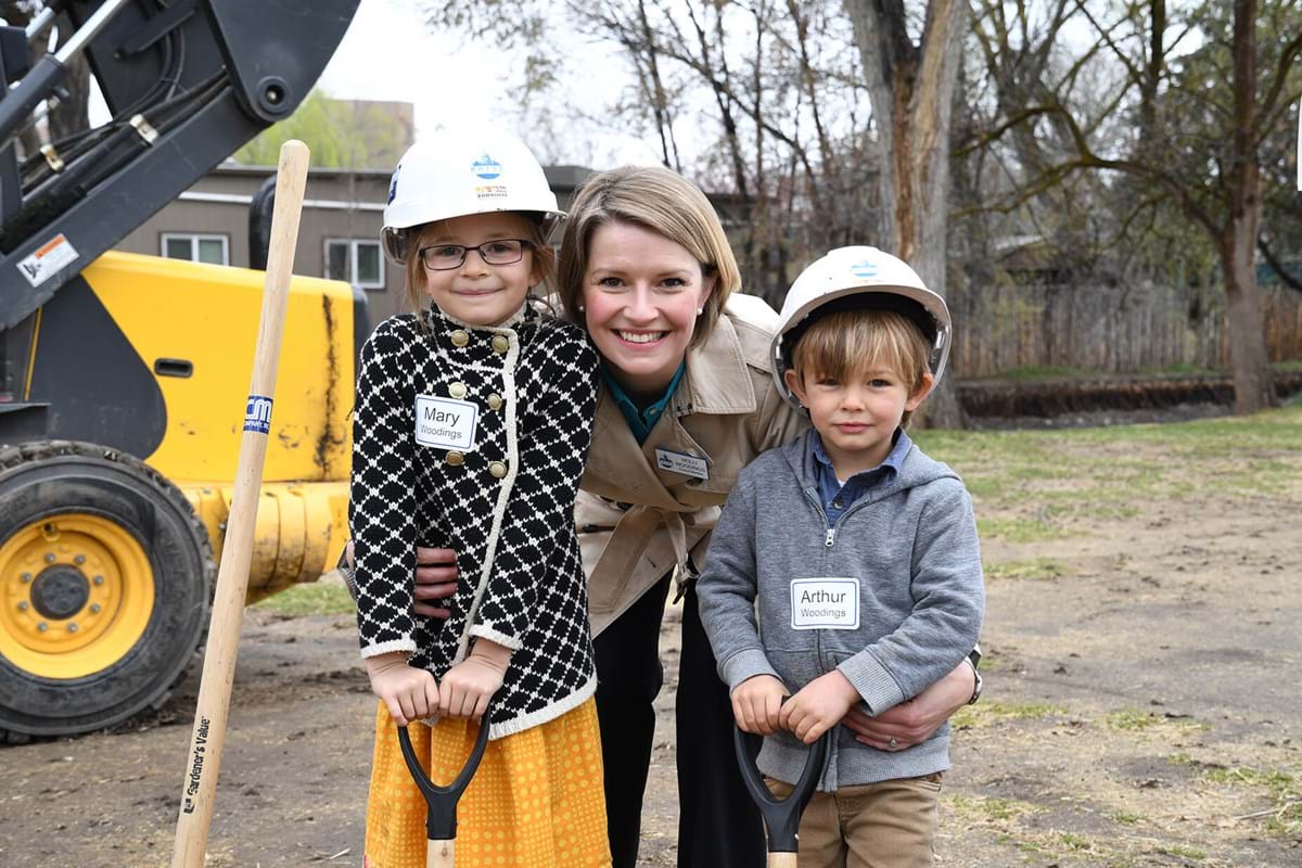 Woman smiling with two children wearing hard hats