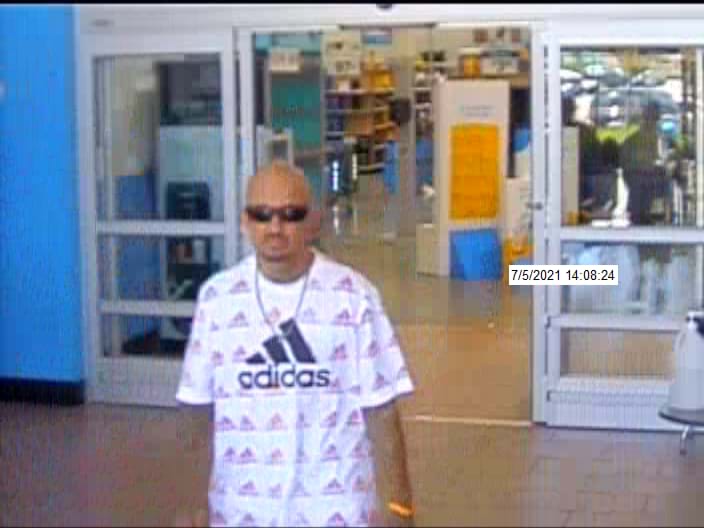 man leaving store with white tshirt and sunglasses