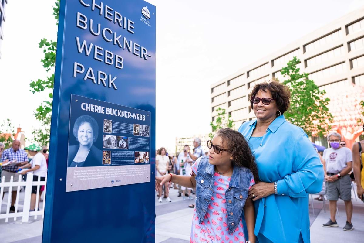 Cherie Buckner-Webb and child look at park sign with her name on it.