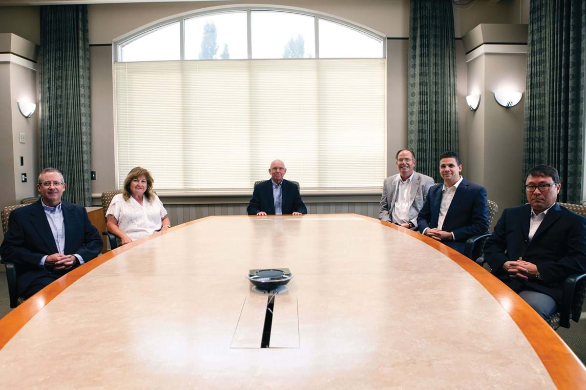 Group of six people sit around a large table.