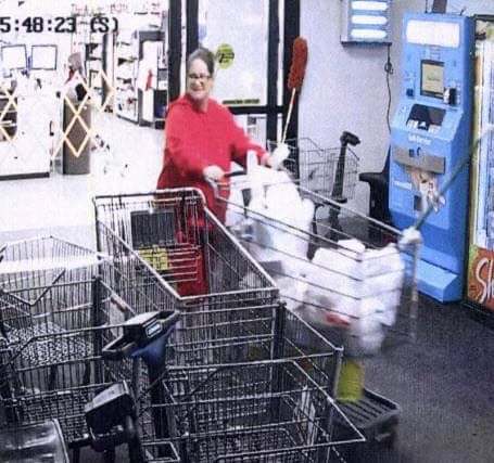 Woman wearing glasses and a red sweater pushing a shopping cart