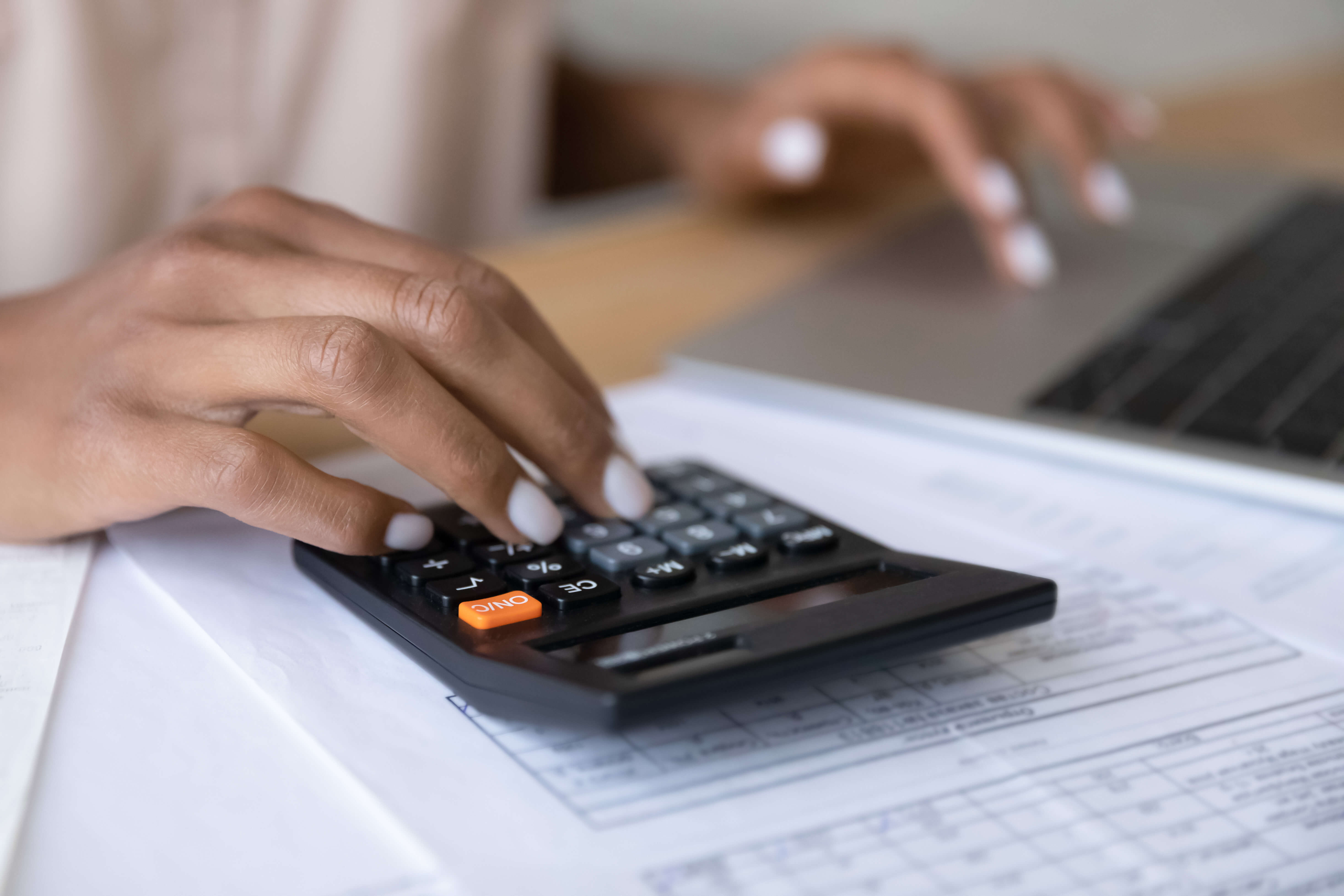 Woman using a calculator and a laptop
