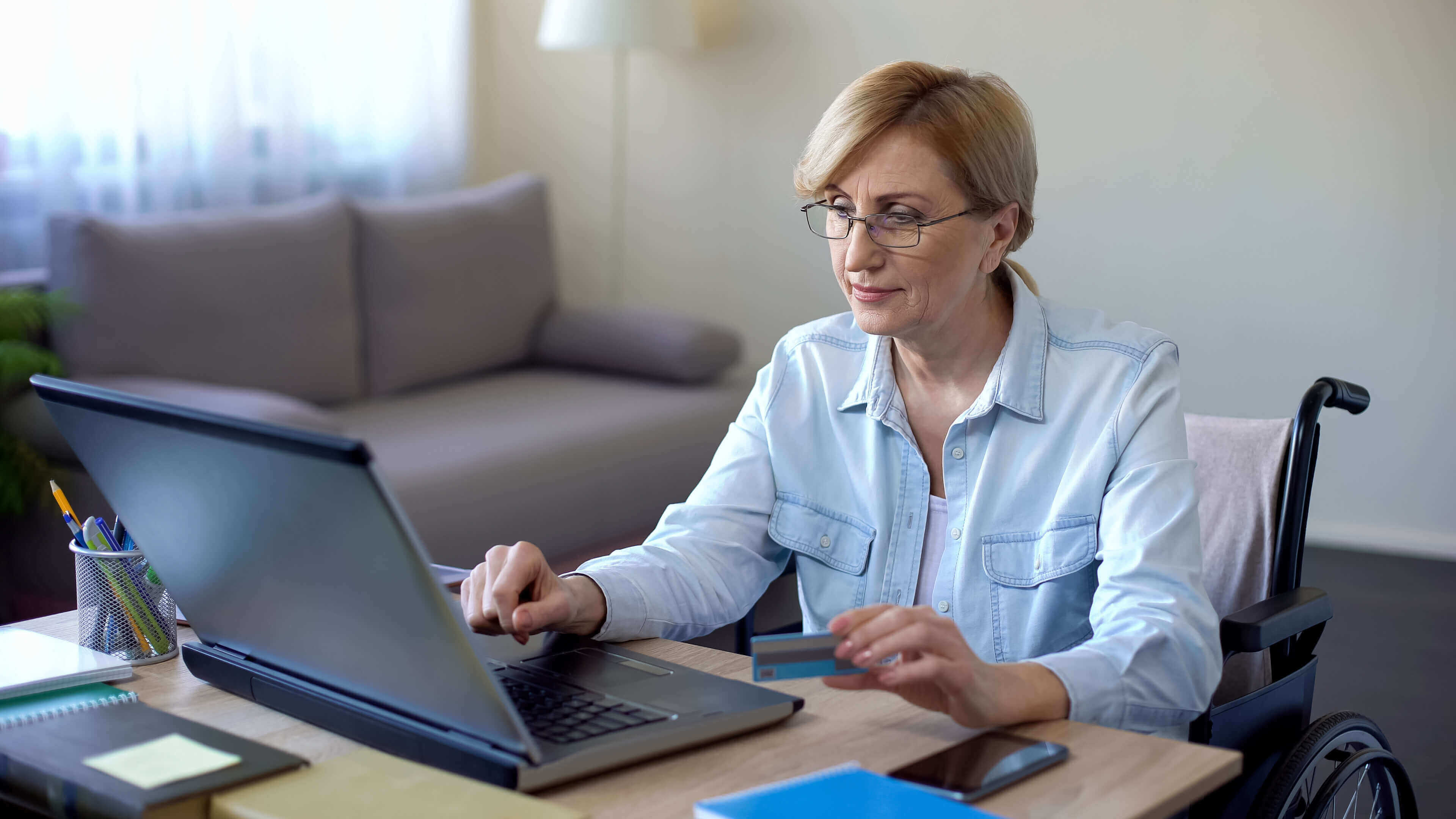 Woman holding a credit card and paying a bill on her phone.