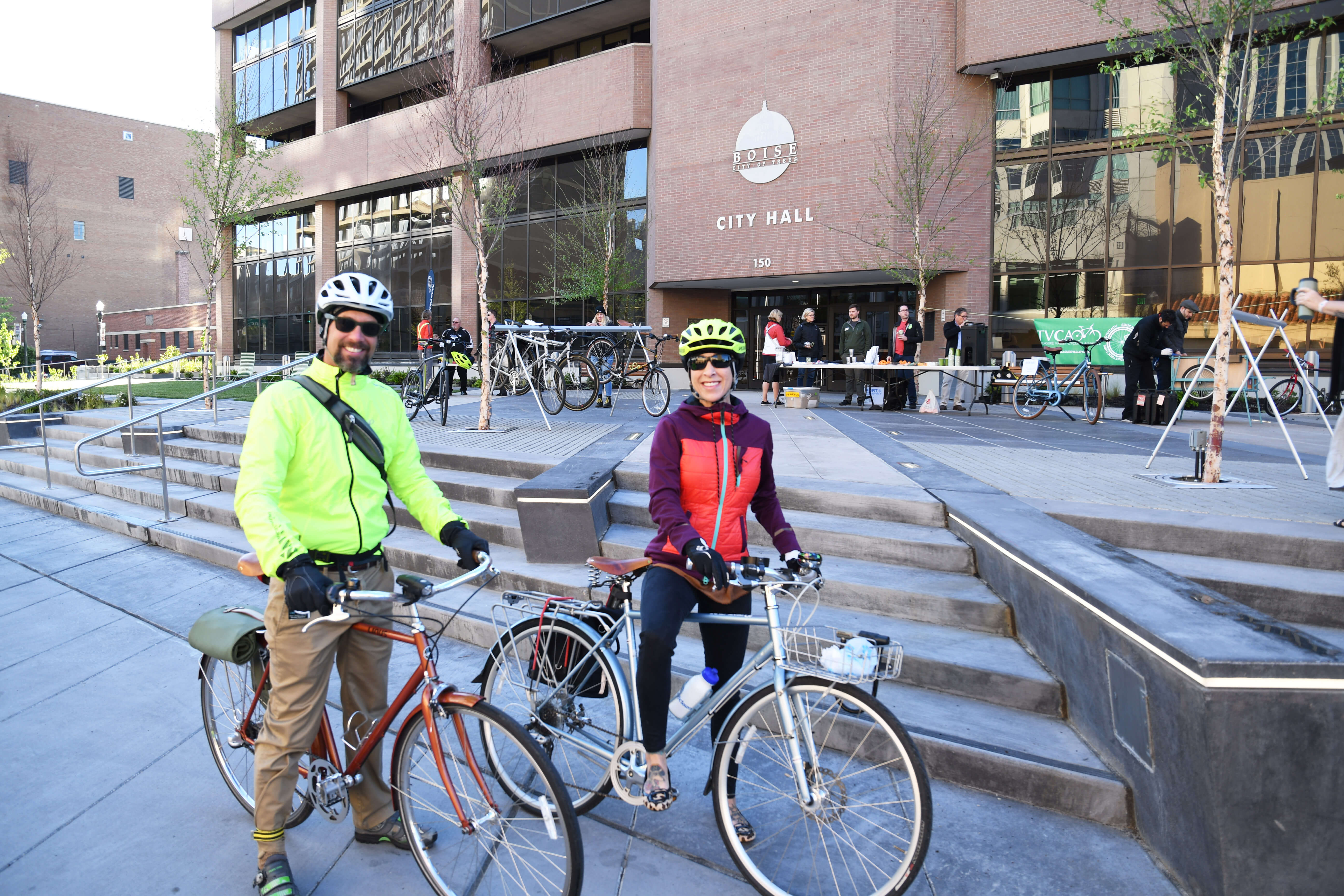 Man and woman posing on bicycles in front of City Hall