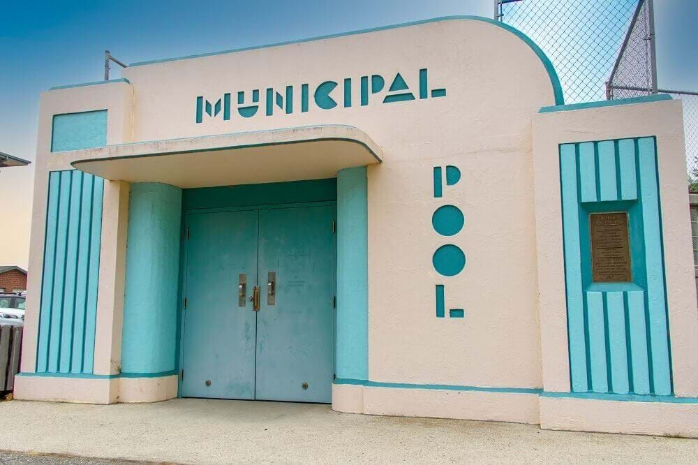 Lowell pool entrance with Municipal Pool written on outside. Tan exterior and blue door and embellishments