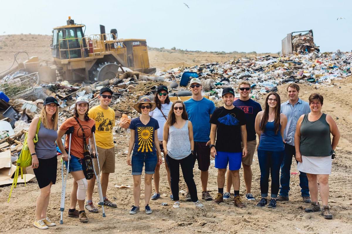 Group of people standing in front of a tractor moving trash