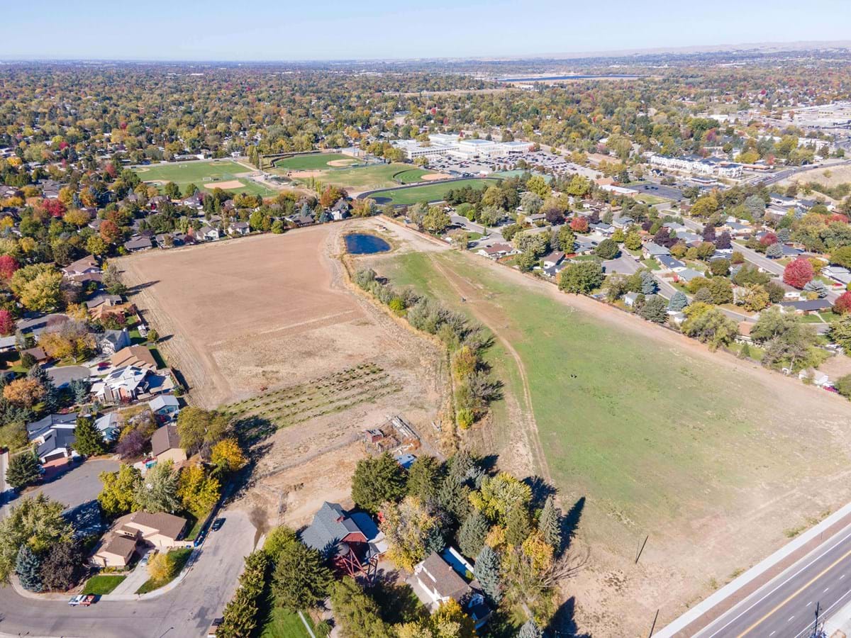 Aerial view of Boise's Spaulding Ranch park site. Photo shows a red barn and open land surrounded by housing.