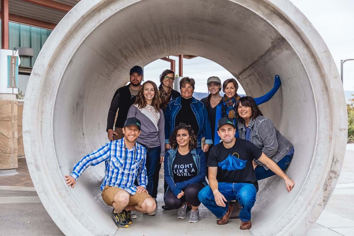 Group of people posing in a large section of pipe