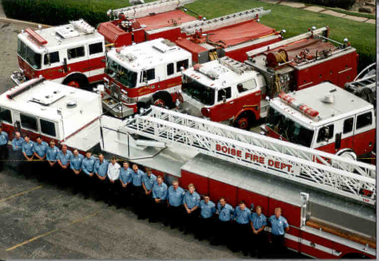 Aerial photo of fire ladder truck and four fire engines with crew of firefighters.