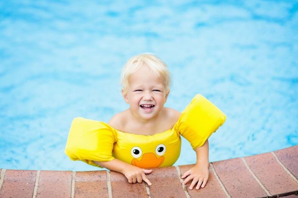 Boy wearing a puddle jumper in the pool.