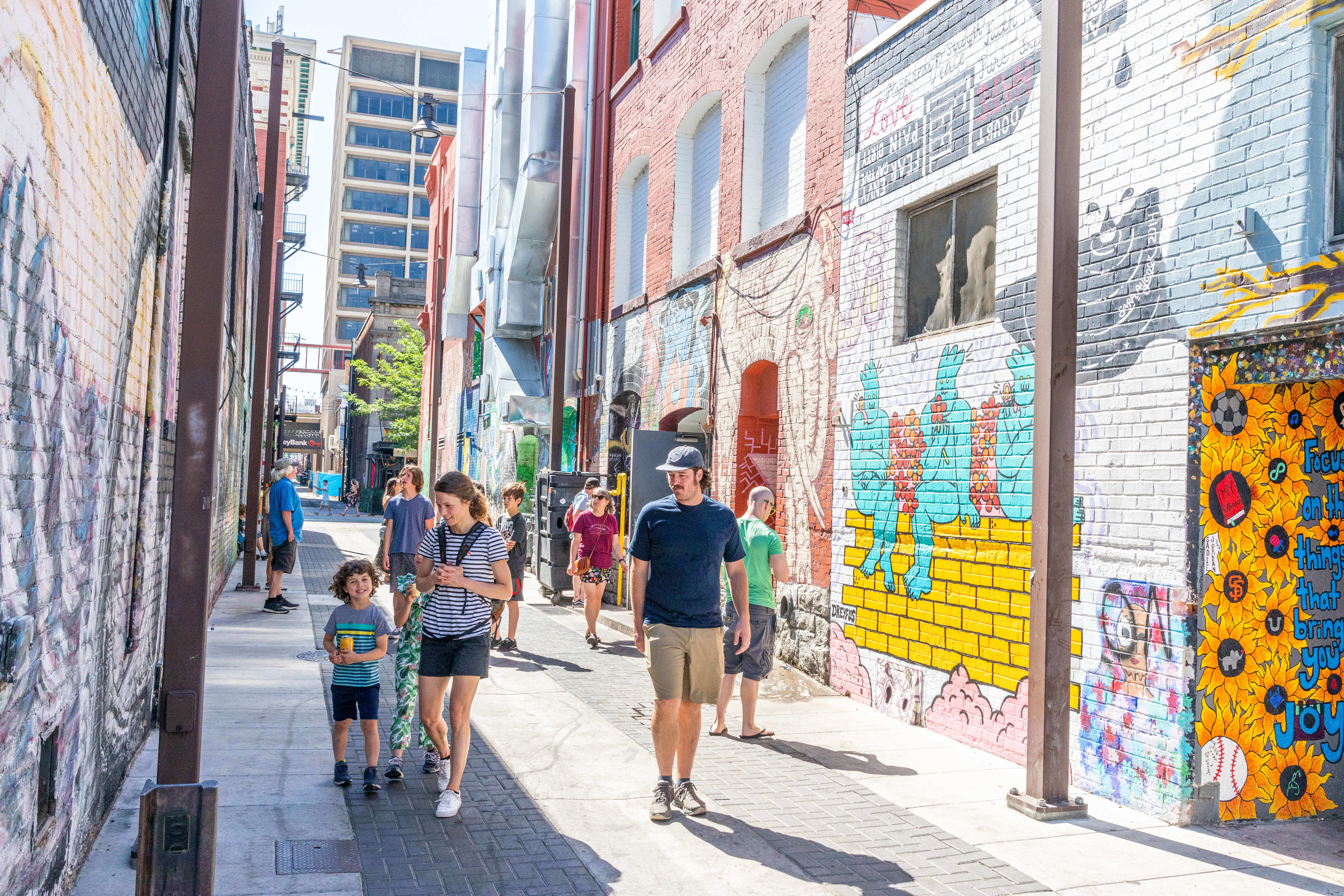 A group of people walking down freak alley looking at the artwork