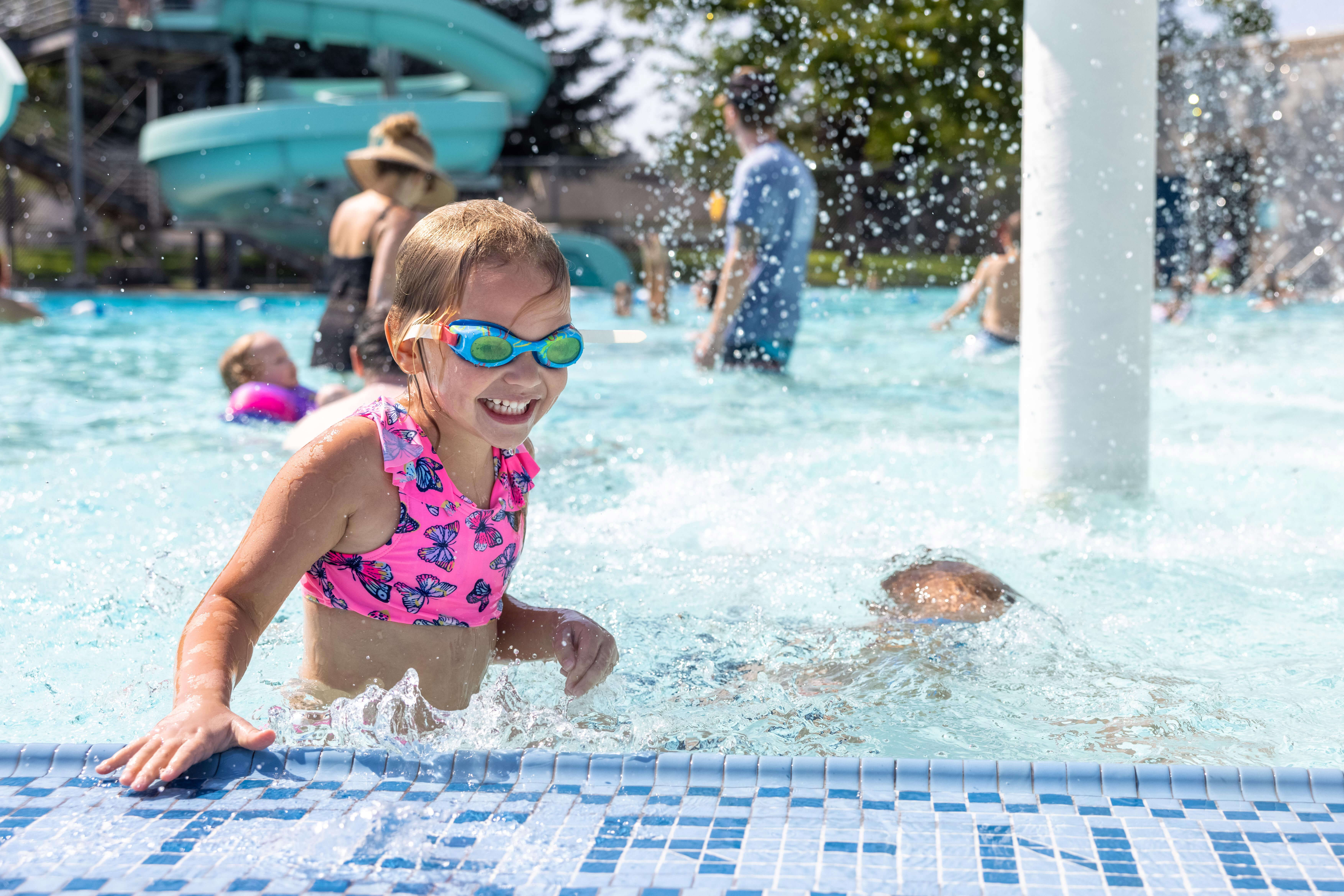 Young girl in a pink swimsuit and goggles plays in Ivywild pool