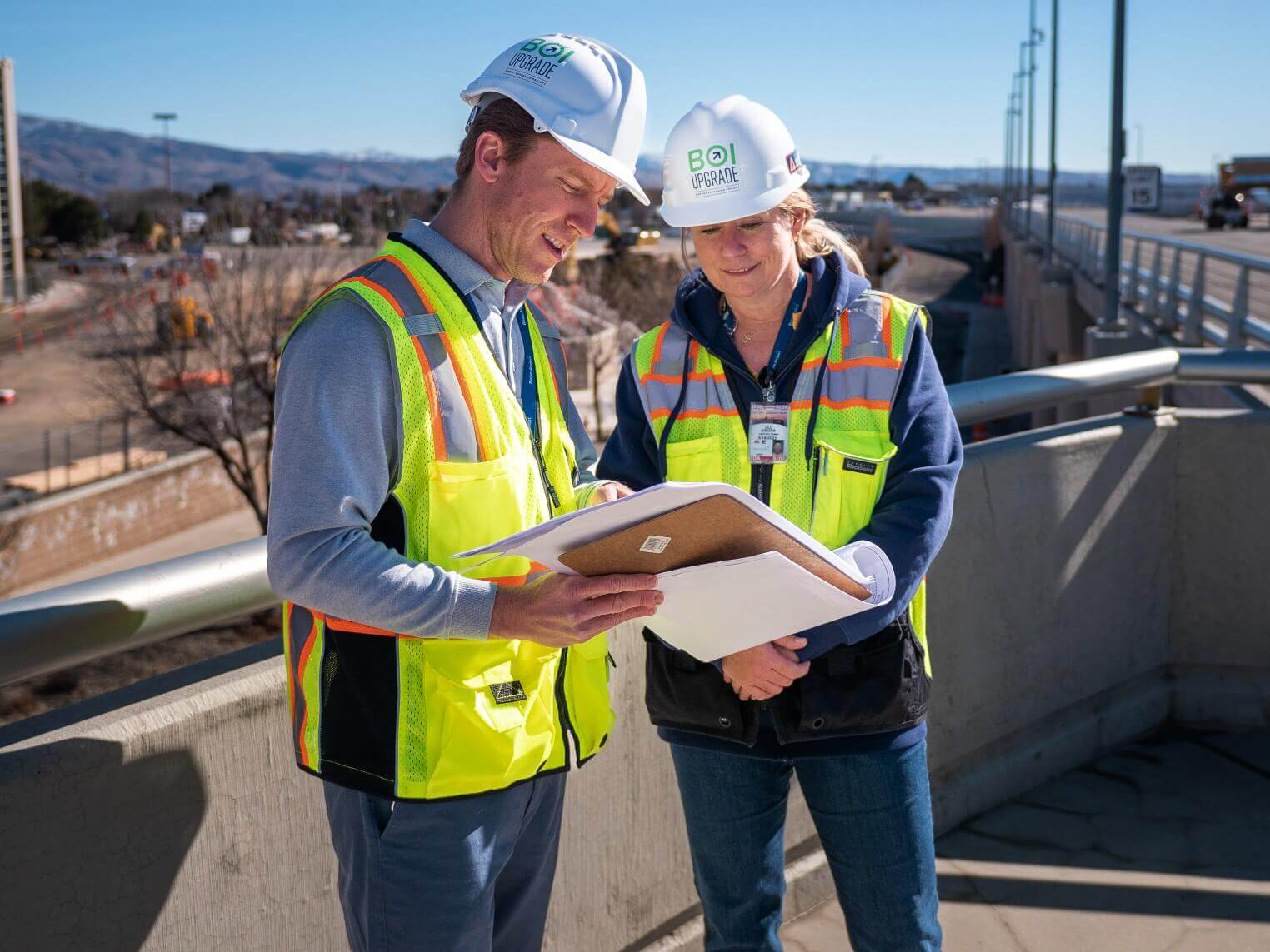 A man and a woman wearing hard hats and safety vests