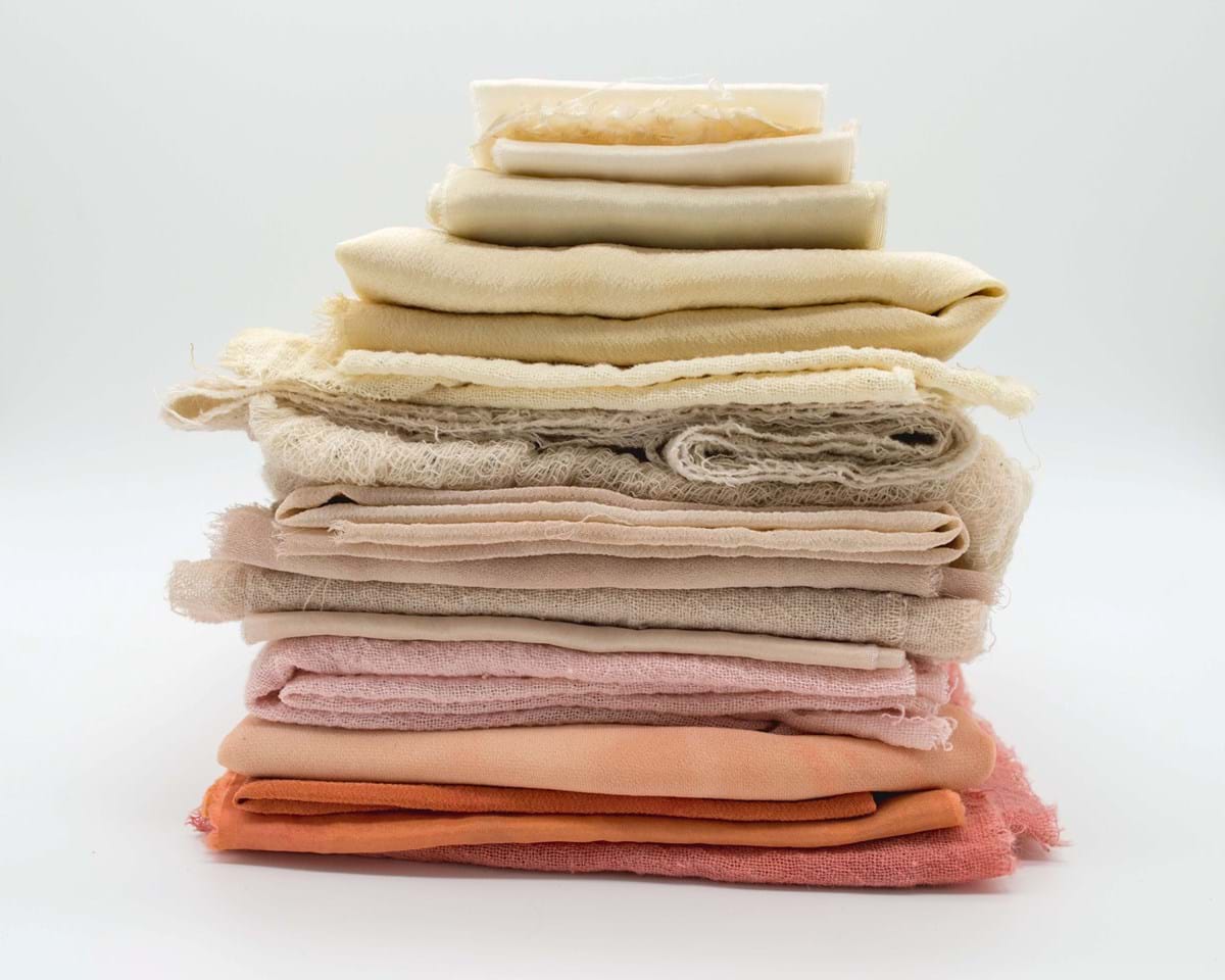 a stack of yellow, pink, cream, and orange cotton textiles