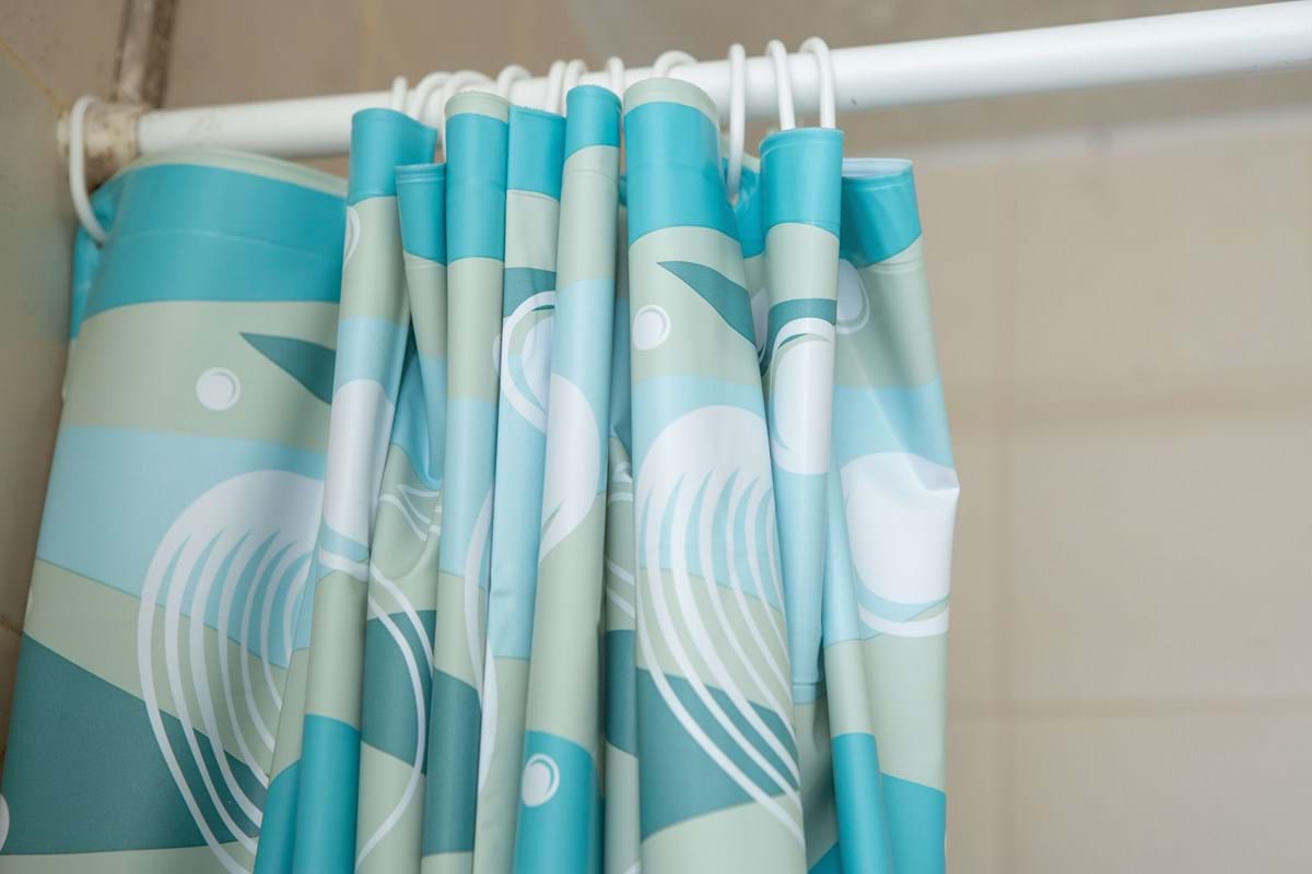 blue shower curtain on a white pole in bathroom