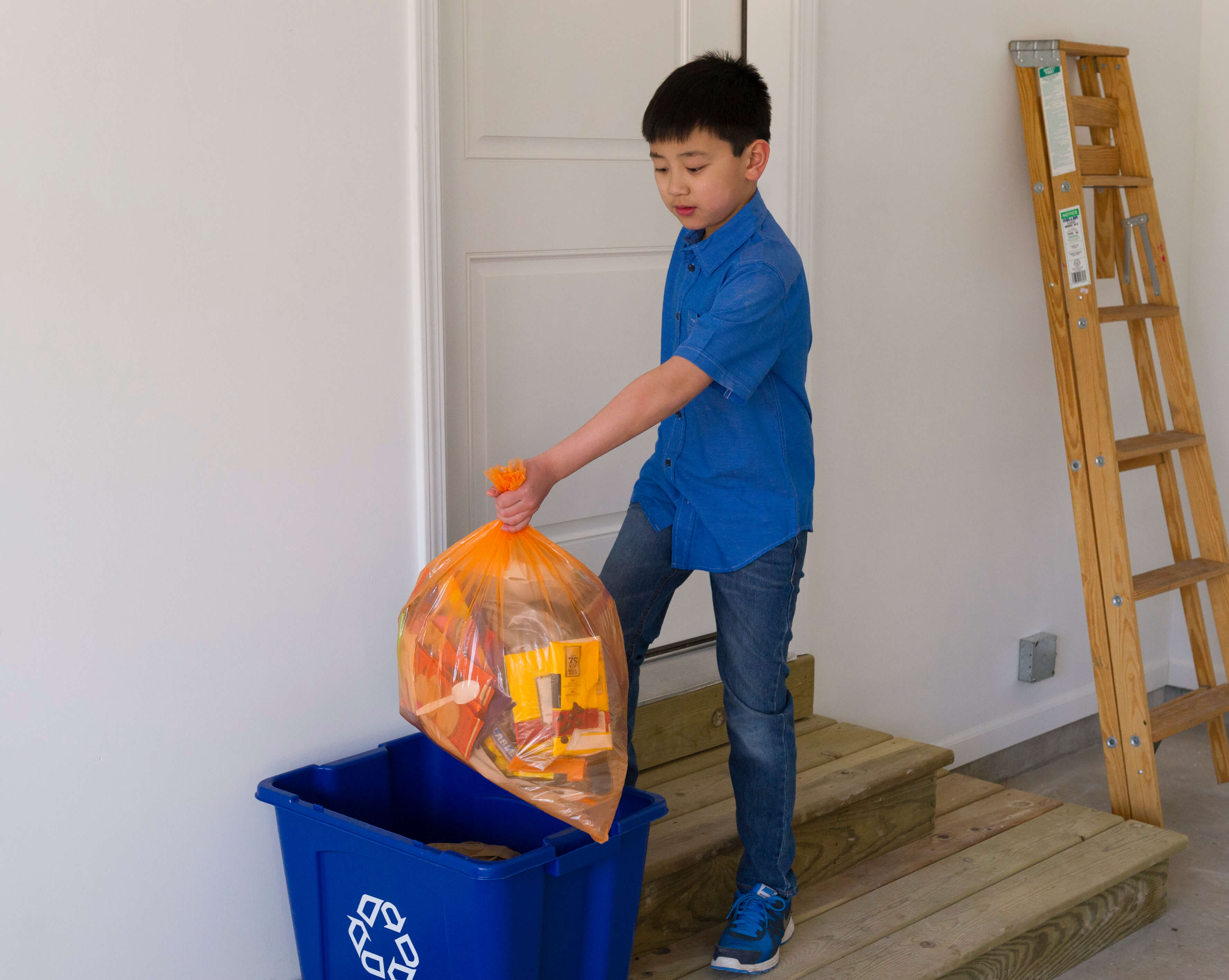 Boy putting Hergy bag into a recycling bin