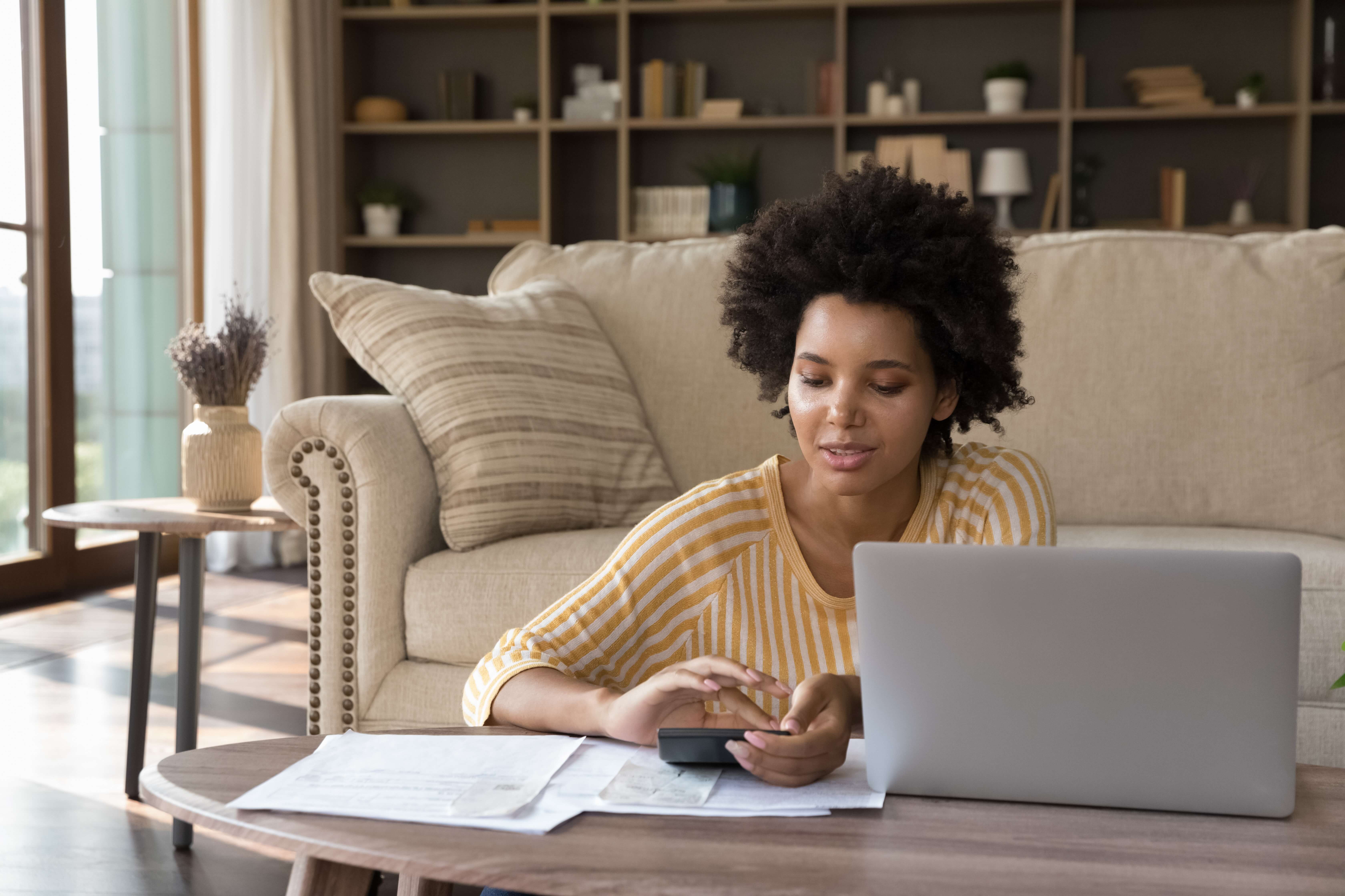 woman sitting on the ground looking at a computer with papers next to it