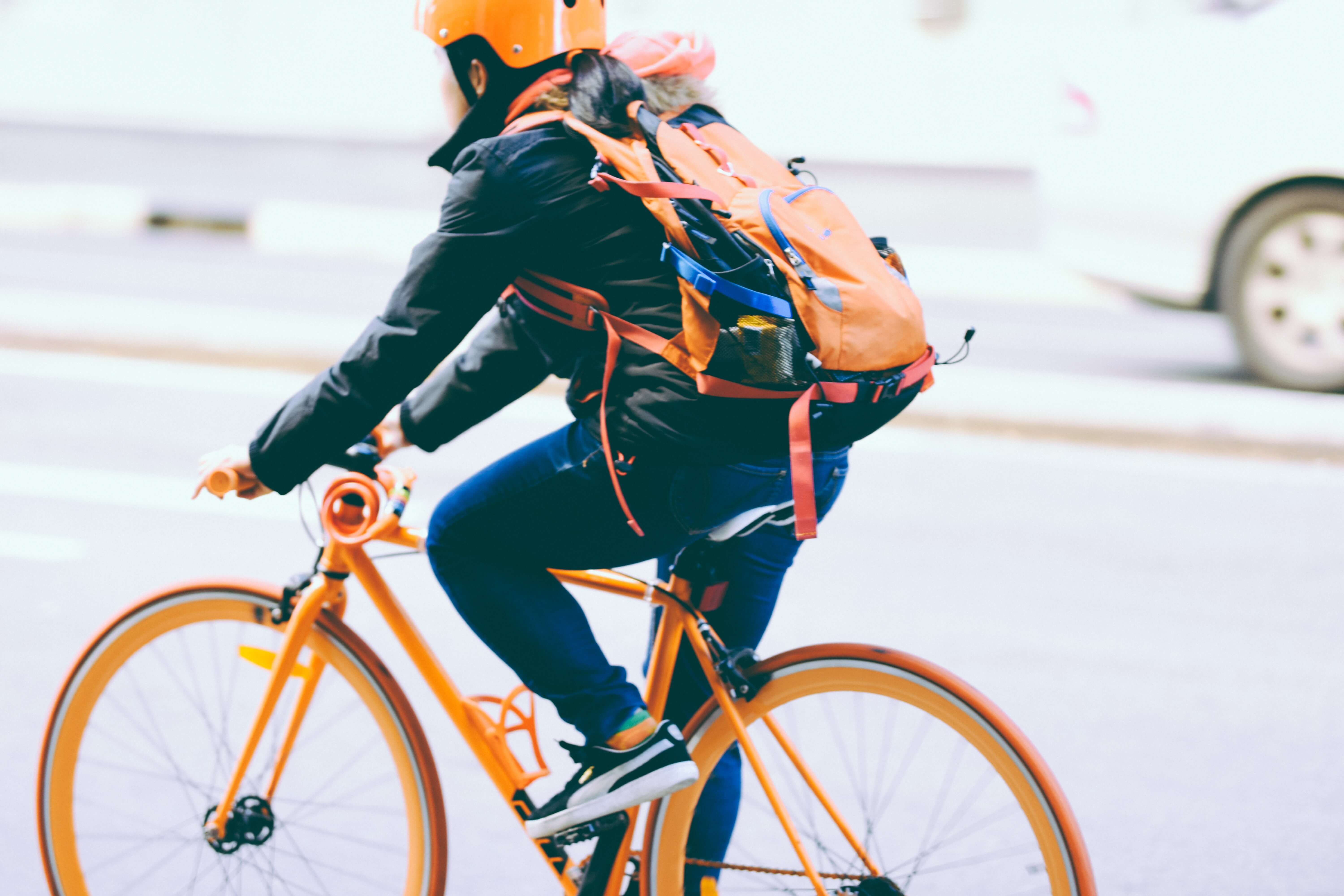 Person riding bike in street with orange helmet and orange bike