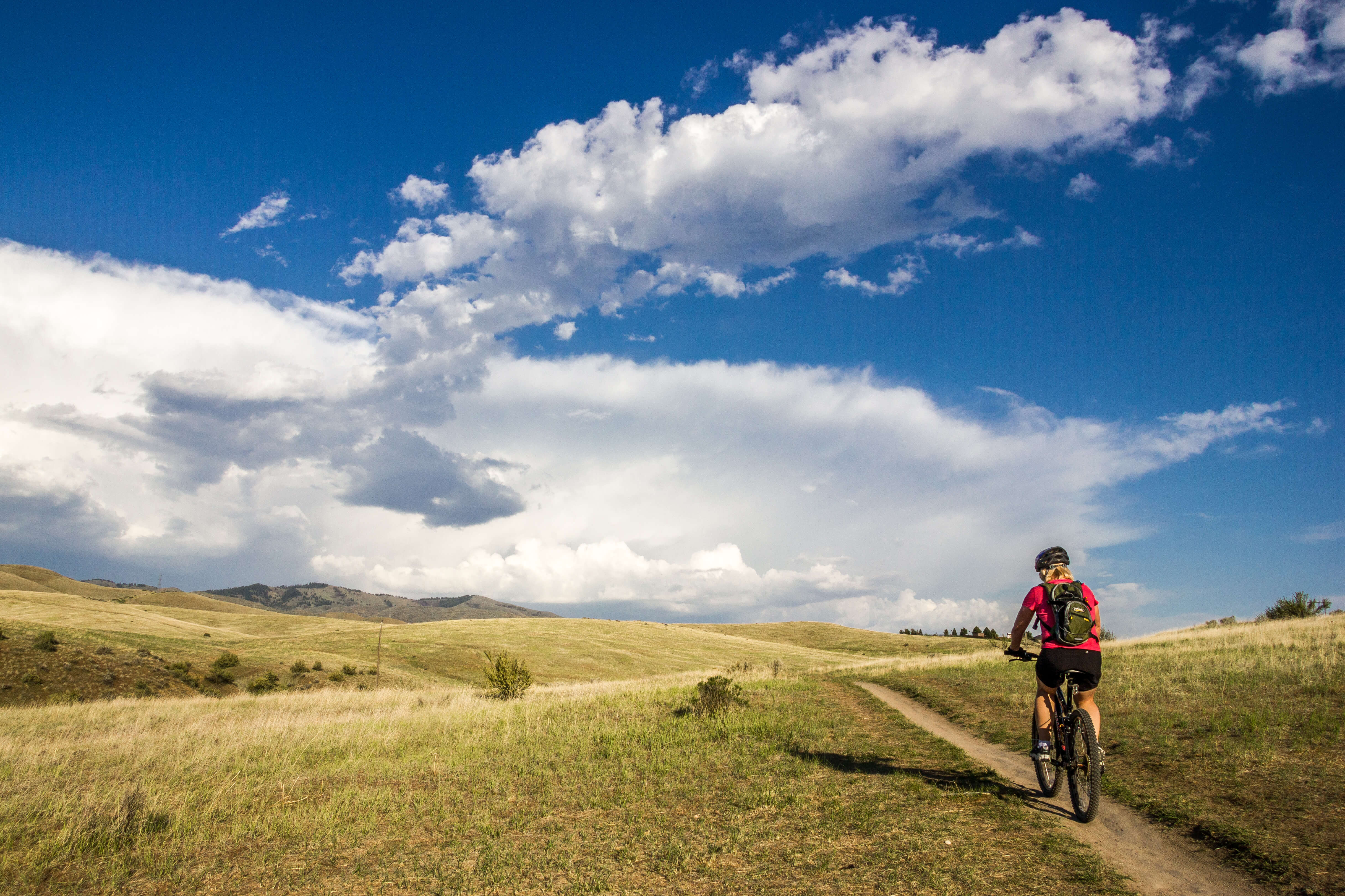 Man mountain biking in foothills with blue skies