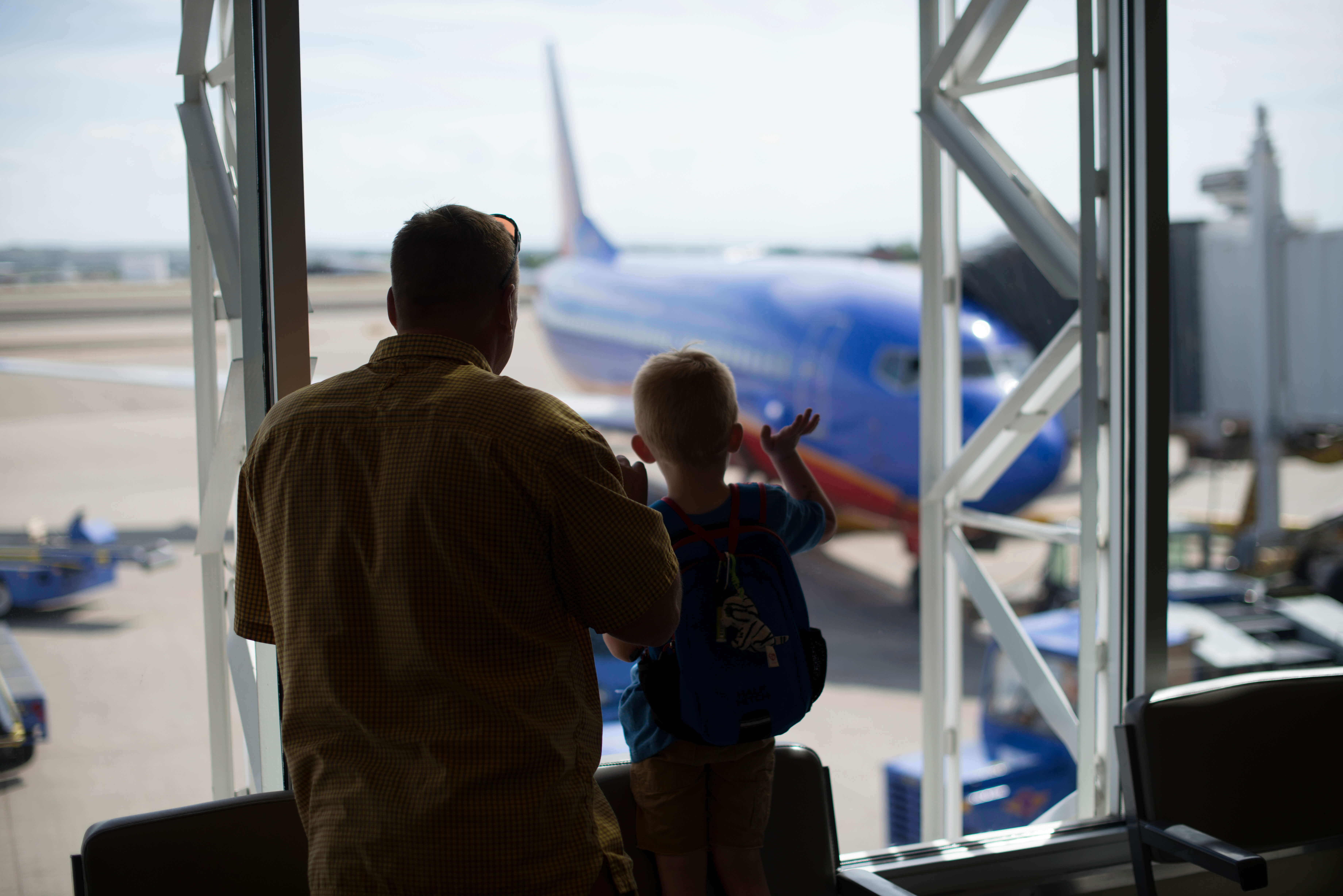 Man and son looking out window to view planes at Boise Airport