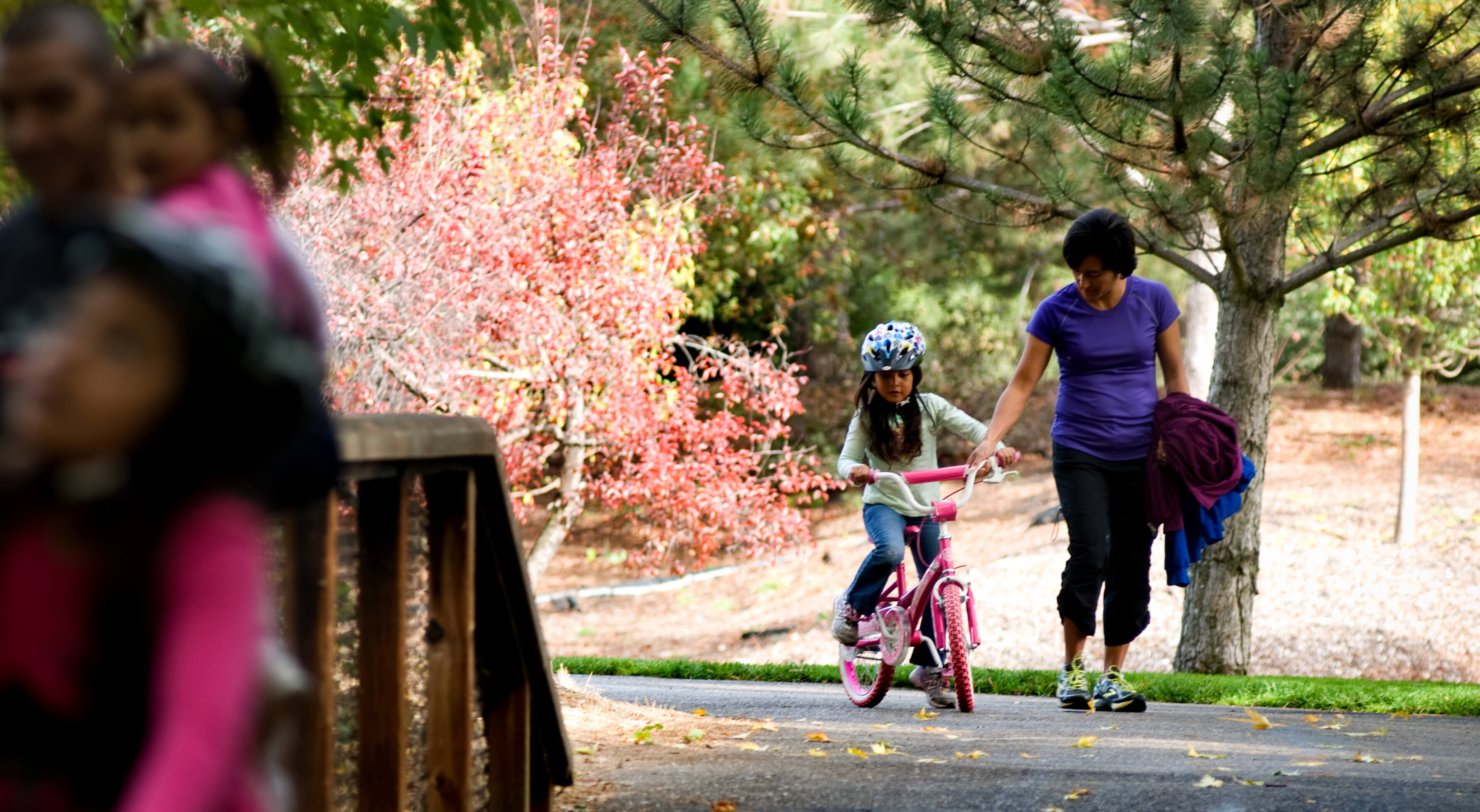 Woman walking with little girl riding her bike