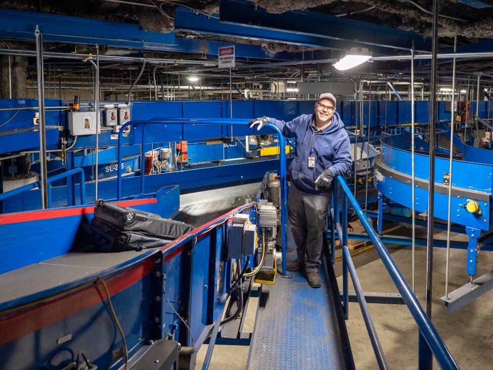 A maintenance tech in front of airport machinery.
