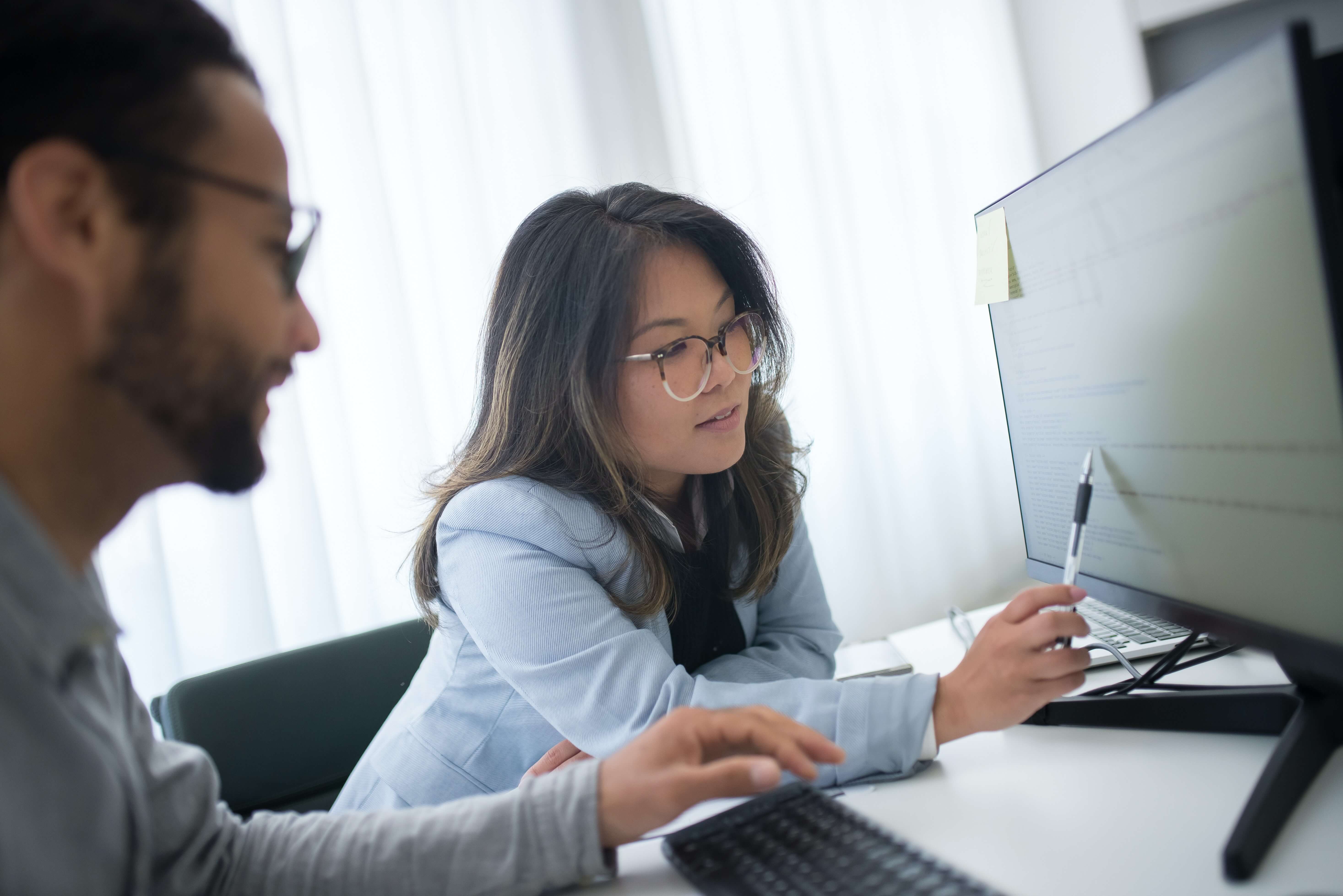Two people review information on a computer monitor.