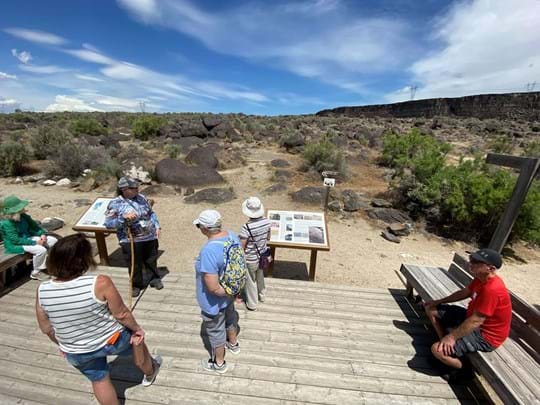 group of people outdoors at celebration park looking at petroglyphs