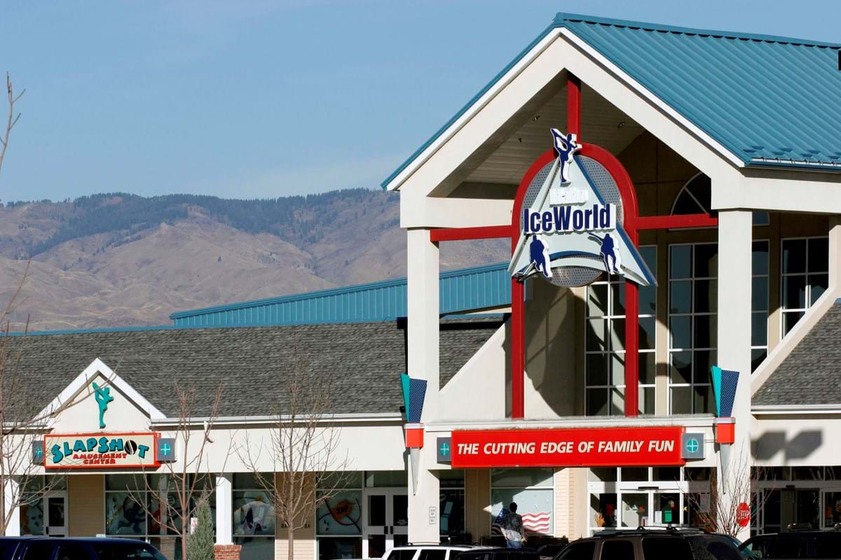 Idaho IceWorld building featuring red pillars and blue roof with foothills in background and blue skies