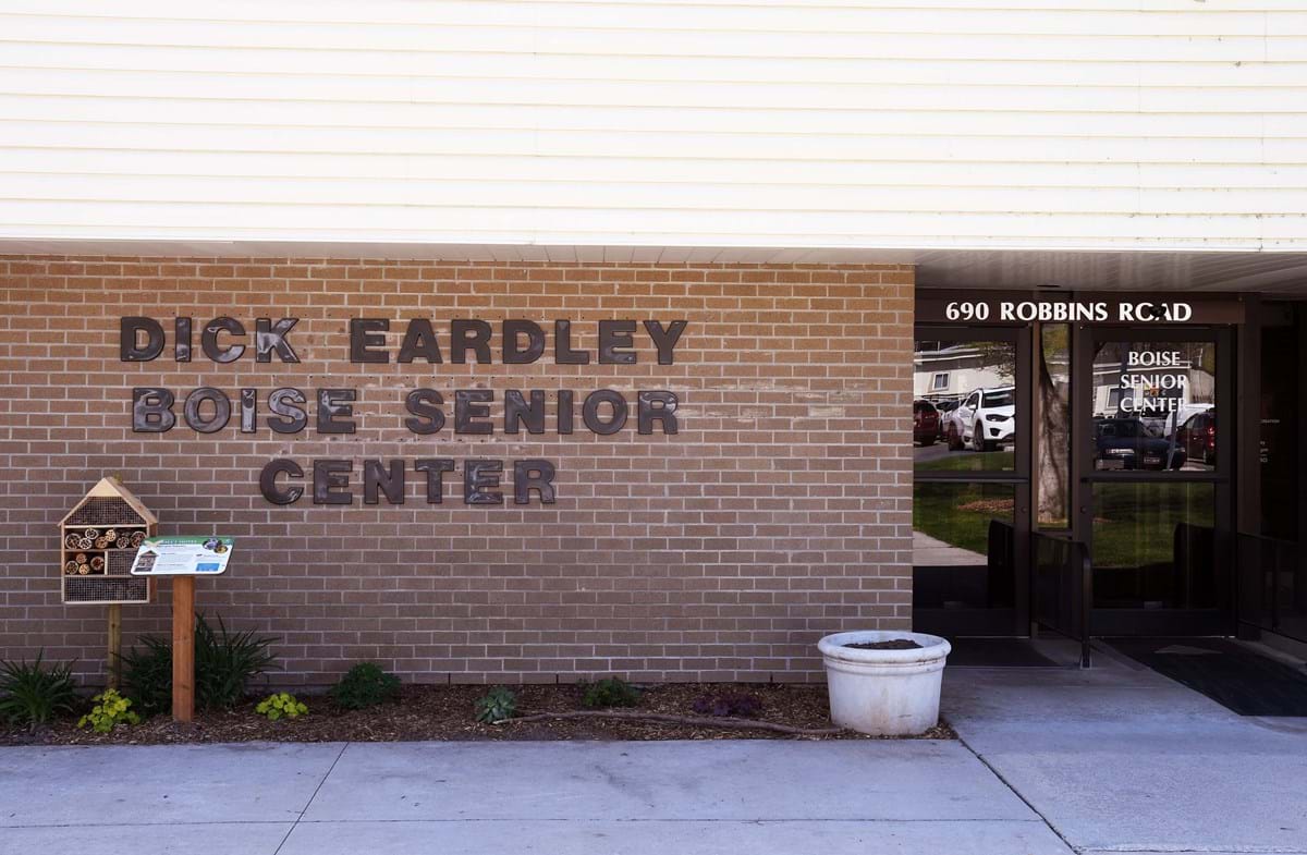 Dick Eardley Senior Center with brick exterior featuring a small pot and bee house next to facility sign