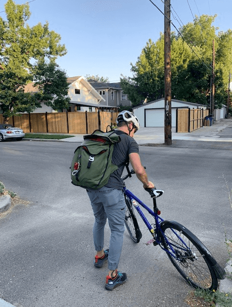 Man wearing a green backpack with a blue bike.