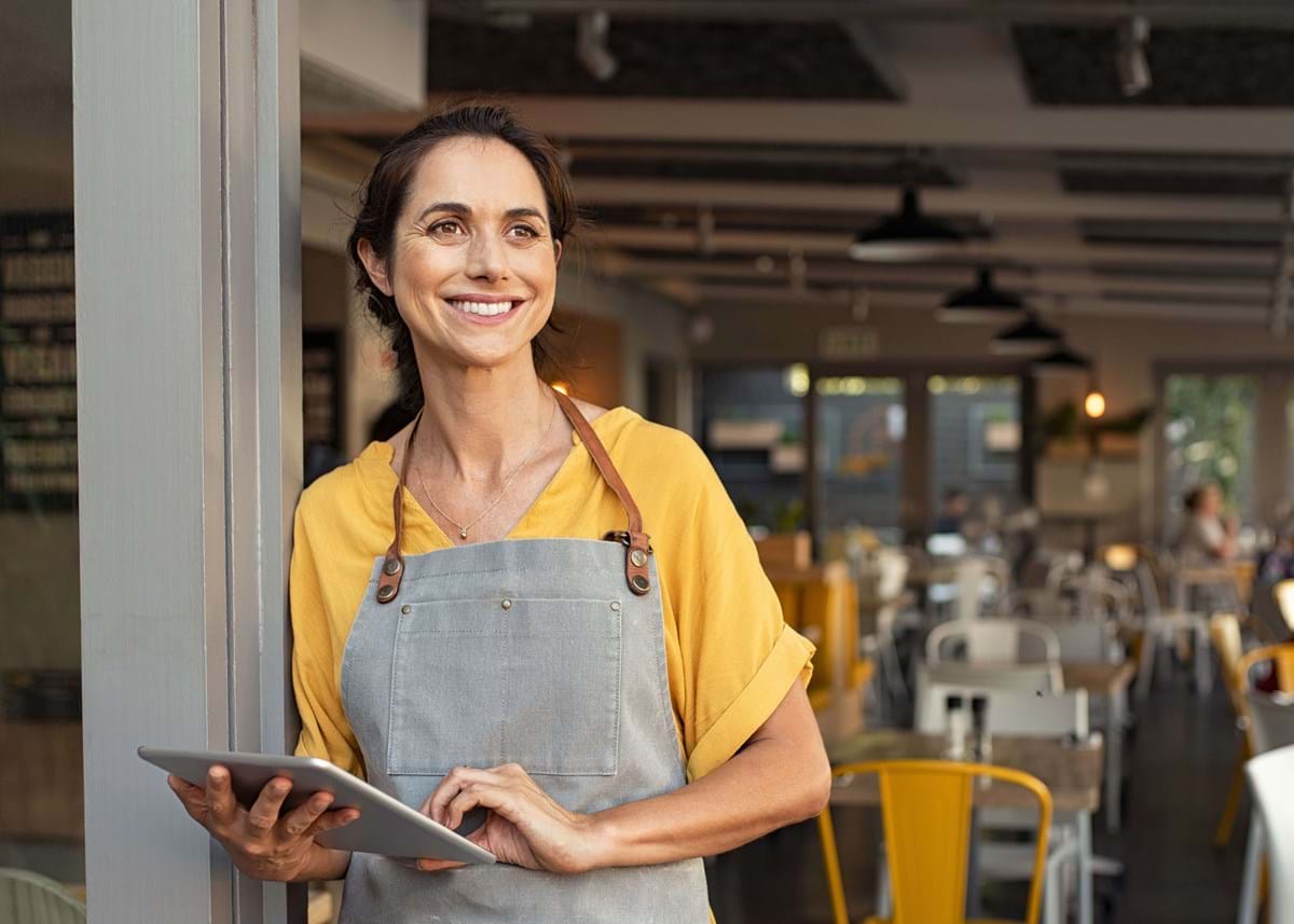 Happy waitress standing in the doorway of a business