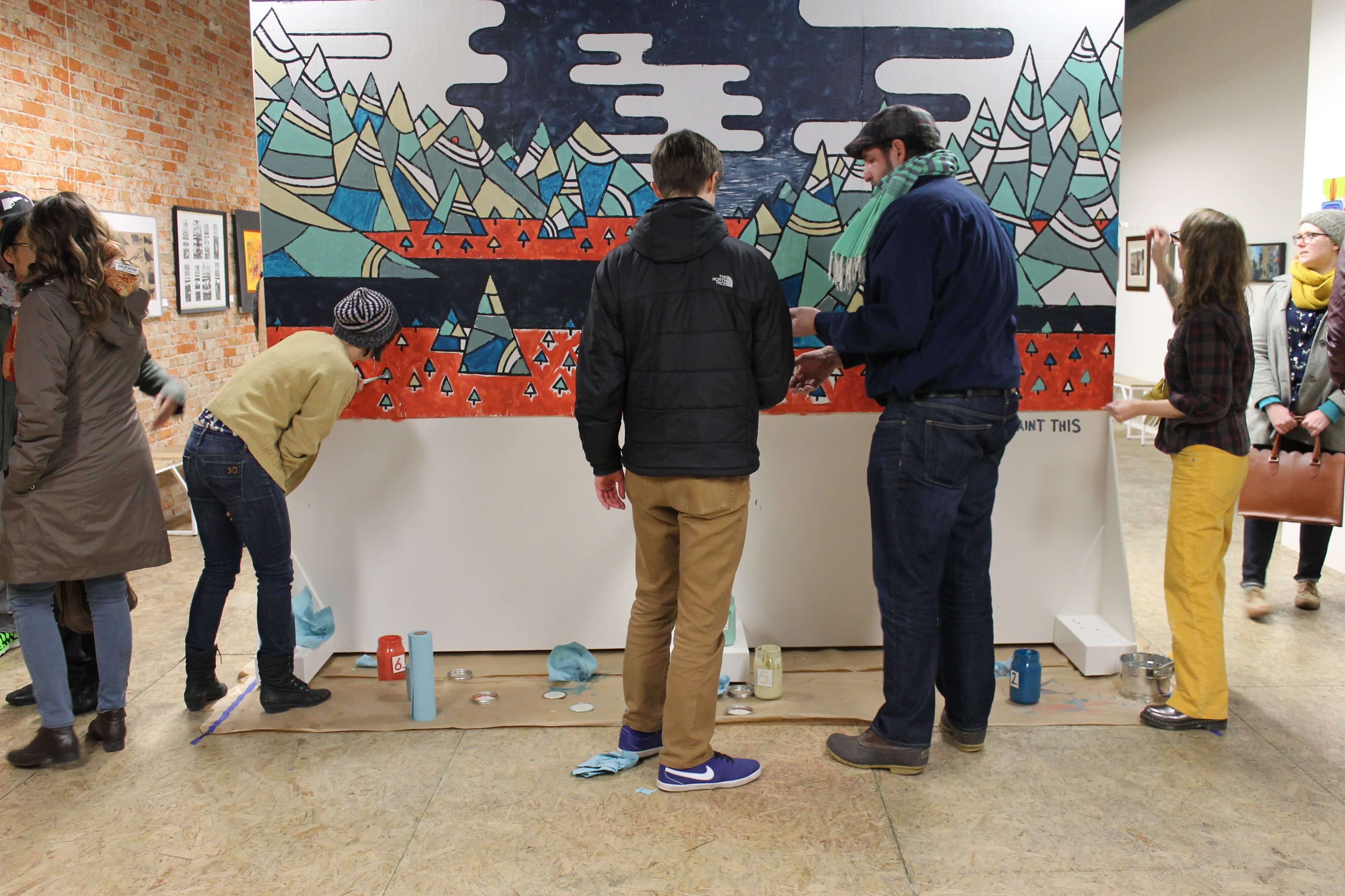 People stand around a large painting examining it.