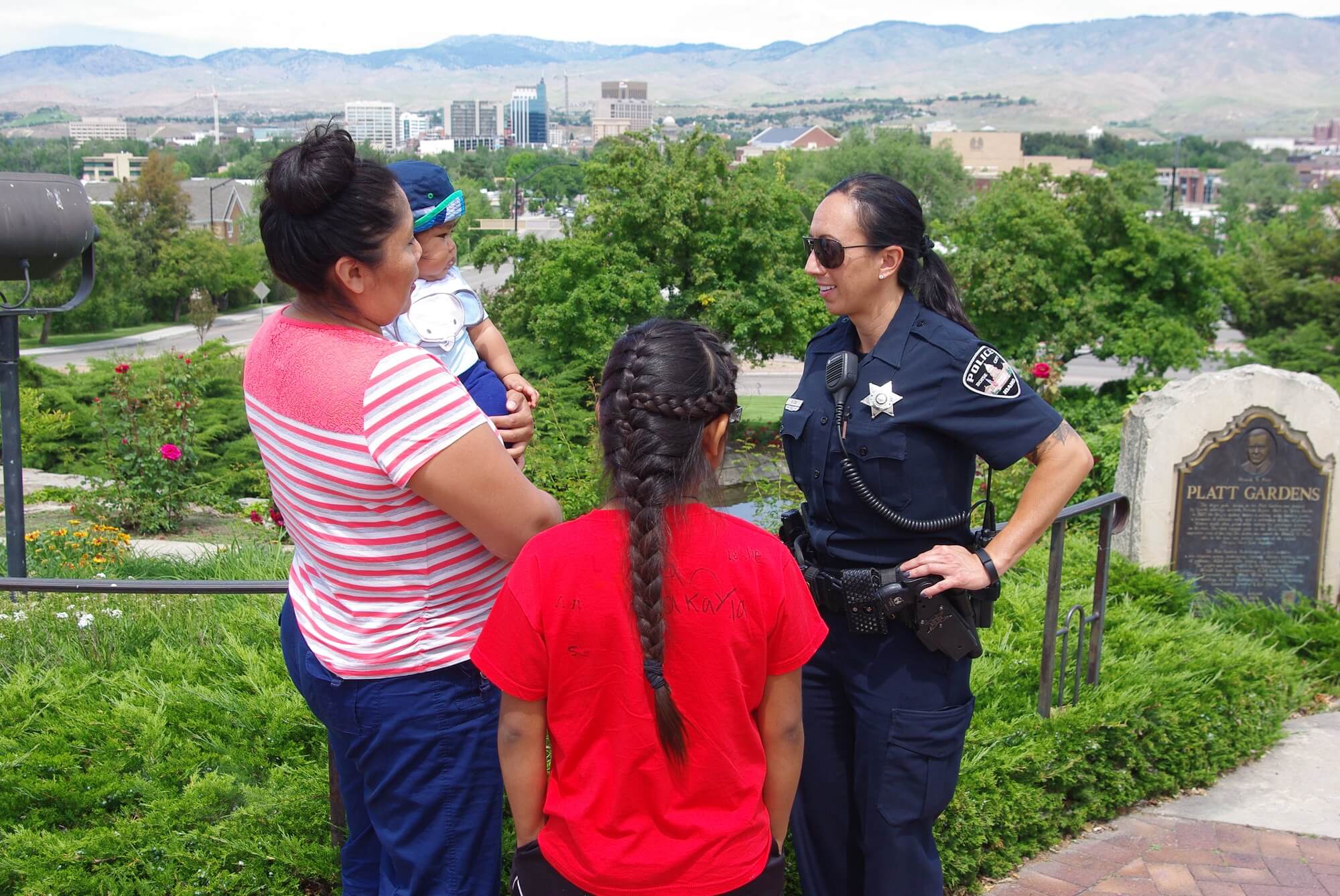 Police officer talking to people with the city skyline in the background.