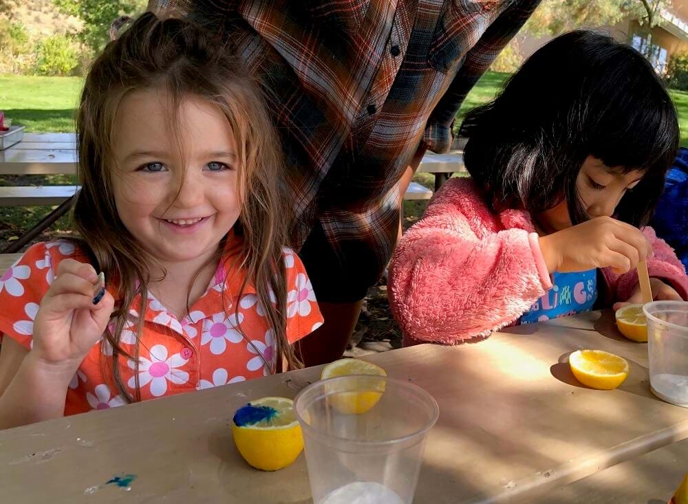 kids painting outside on a picnic table