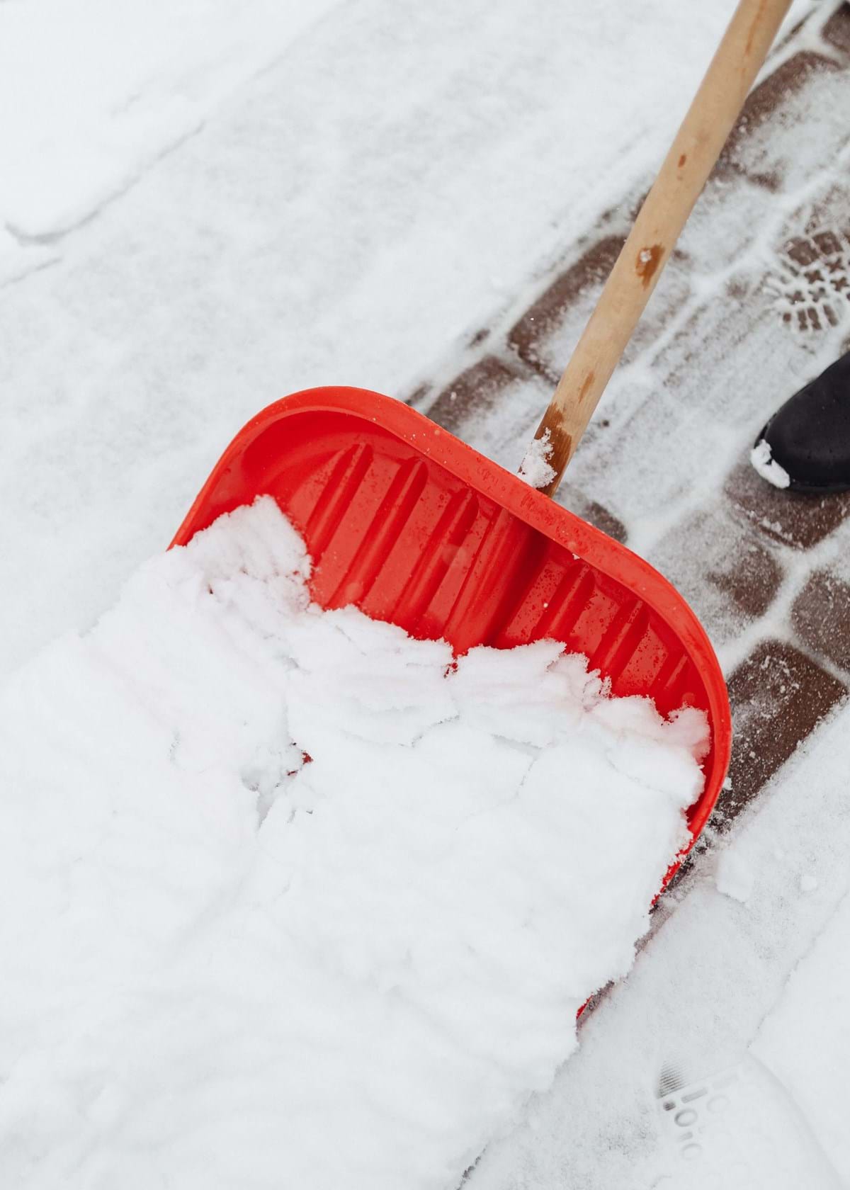 Red snow shovel shoveling sidewalk