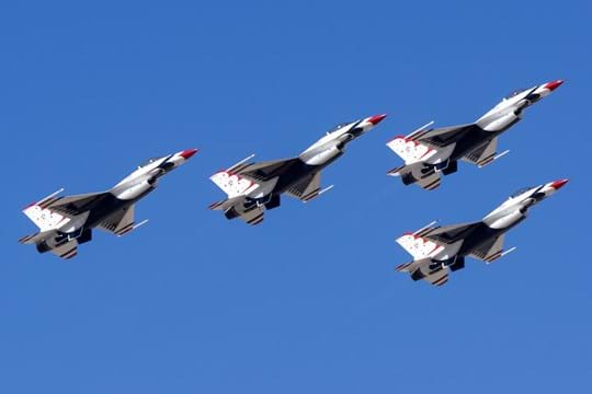 Four jets flying against a bright blue sky.