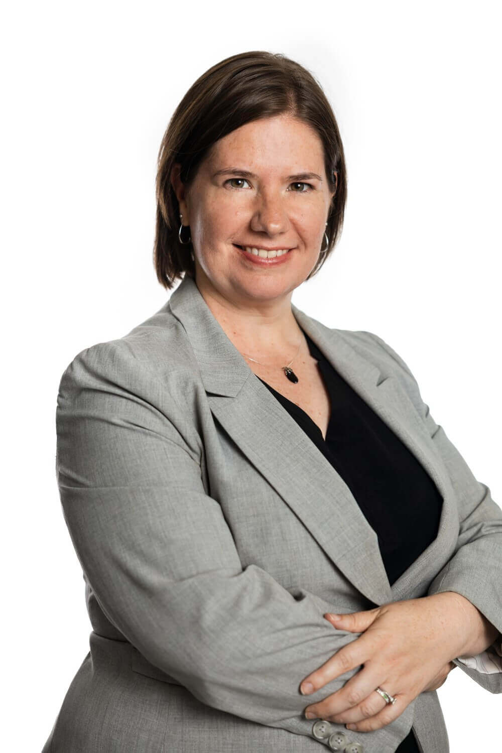 Woman standing with her arms crossed wearing a gray blazer.
