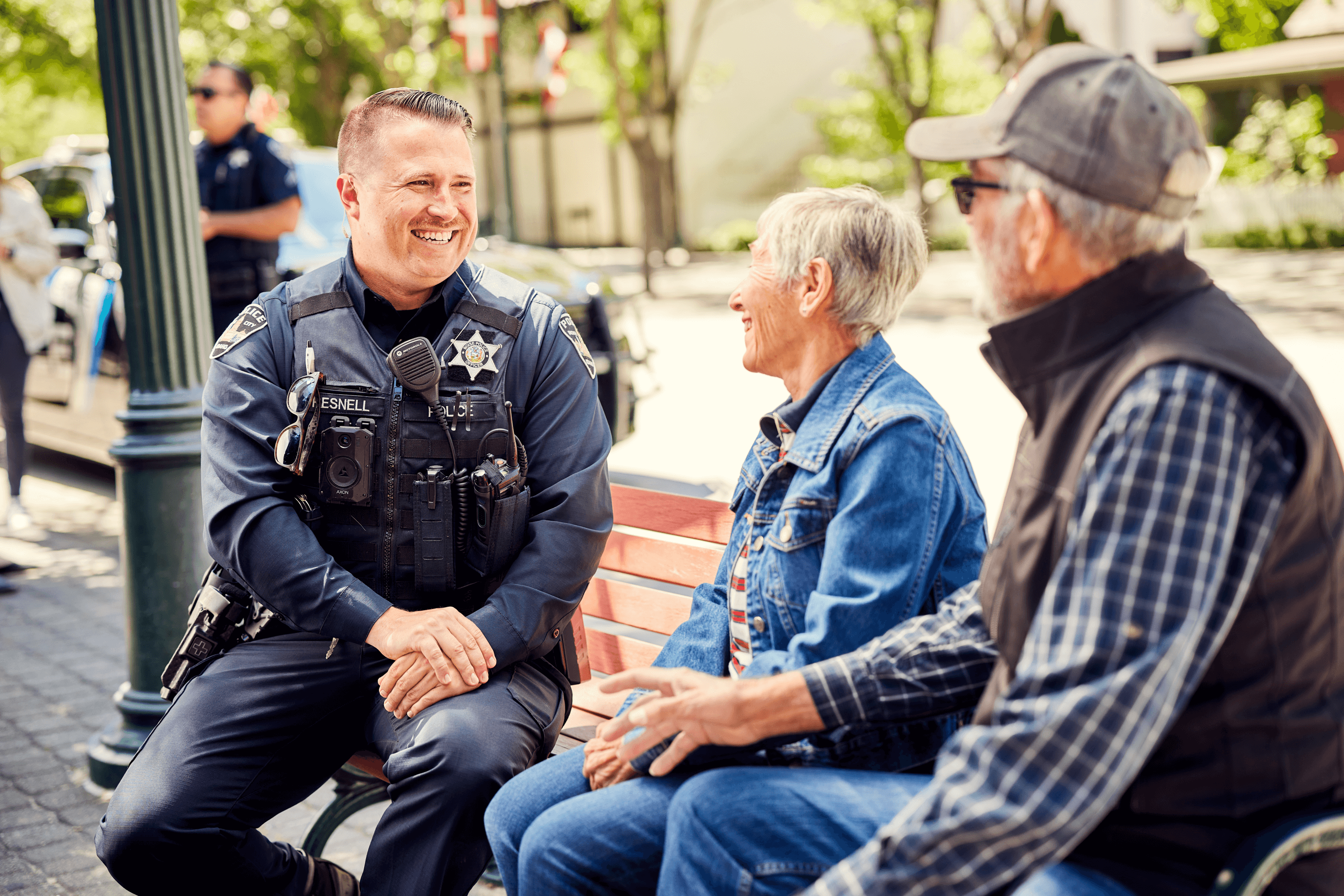 Officer sitting on a park bench with an older couple