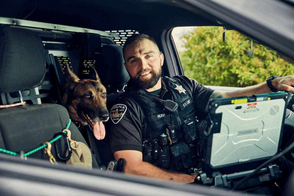 Officer in a police car with K9 unit