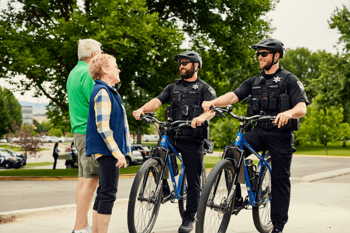 Officers on bikes talking to an older couple on the greenbelt