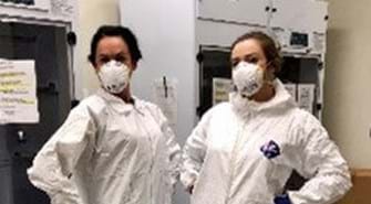 Two CSOs posing in lab gear with face masks on